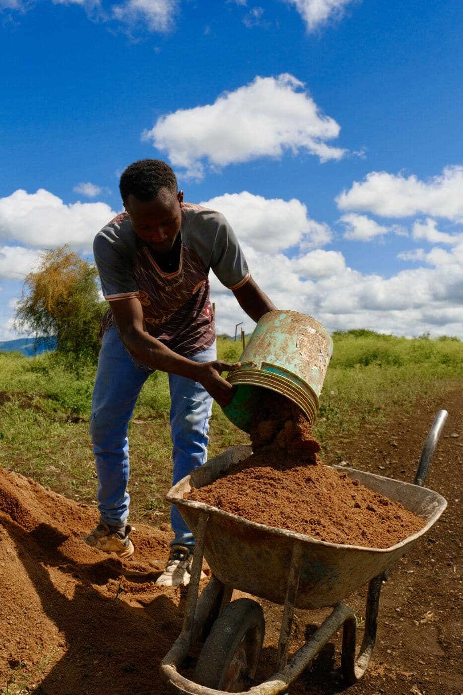 A man shovelling earth into a wheelbarrow during water works at Makuyuni.