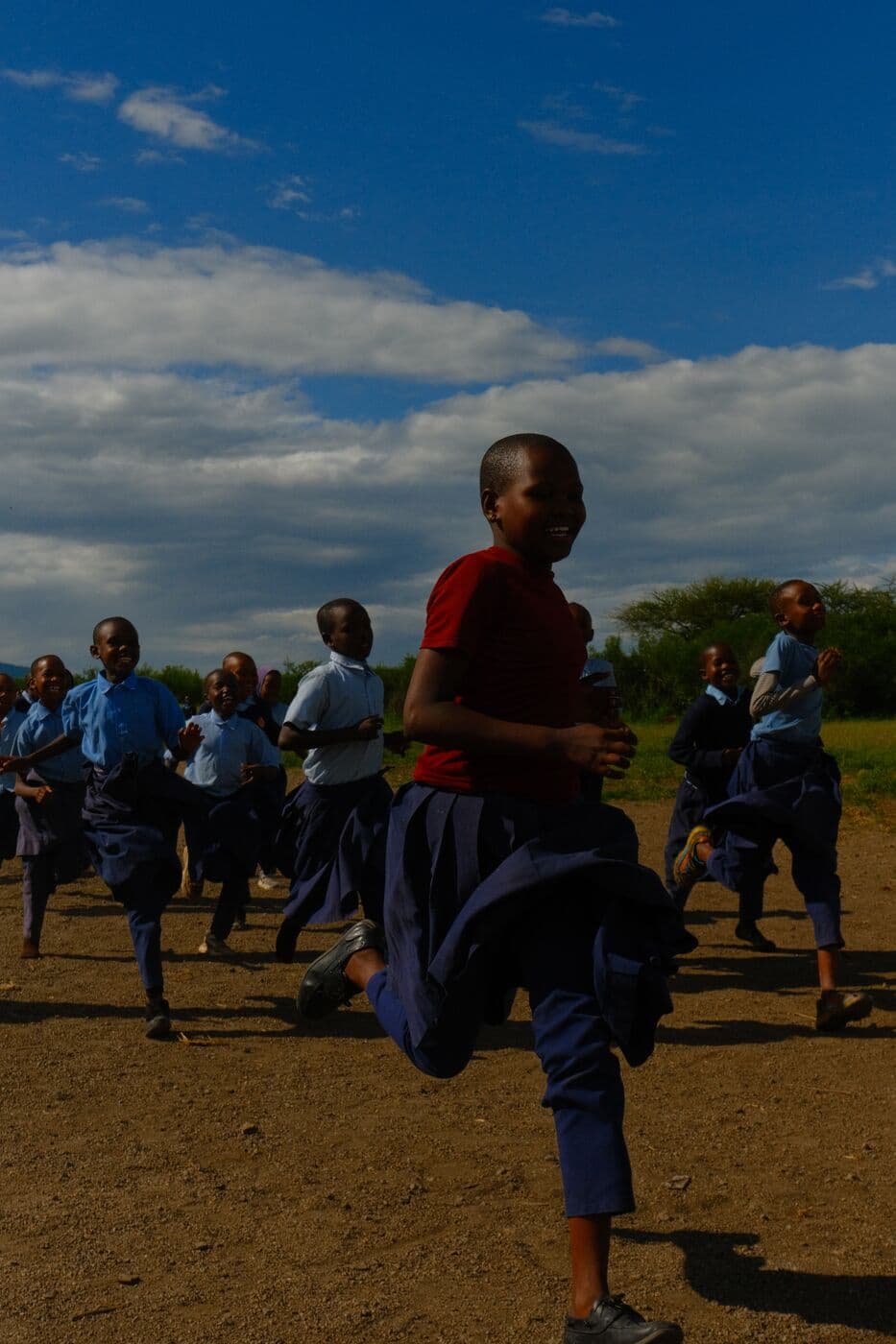 Schoolchildren in uniform running outdoors at Makuyuni.